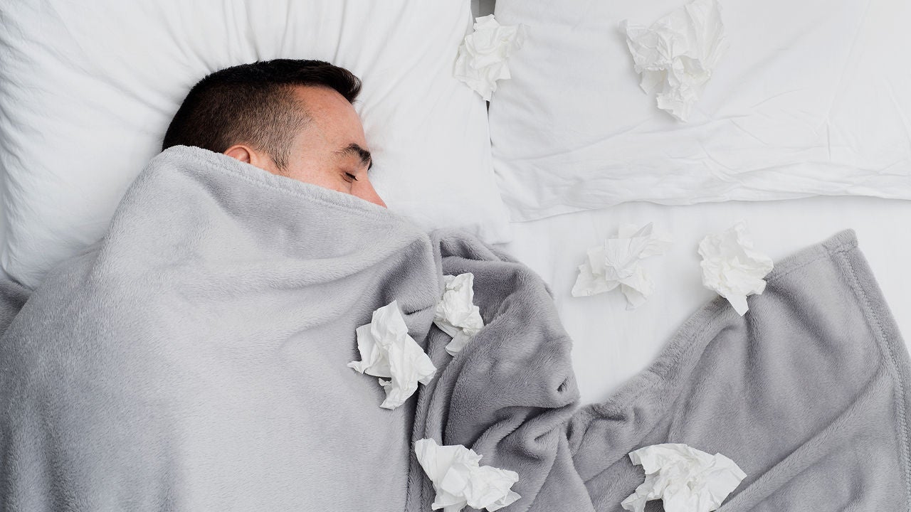 Mann liegt umringt von Taschentüchern und offensichtlich krank im Bett. Bildquelle: ©Adobe Stock/nito