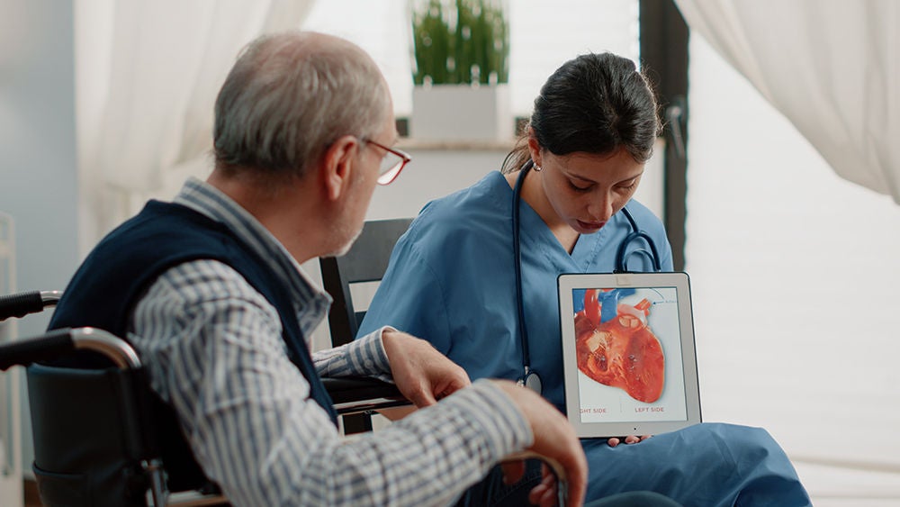Eine Ärztin erklärt einem Patienten den Aufbau des Herzens.