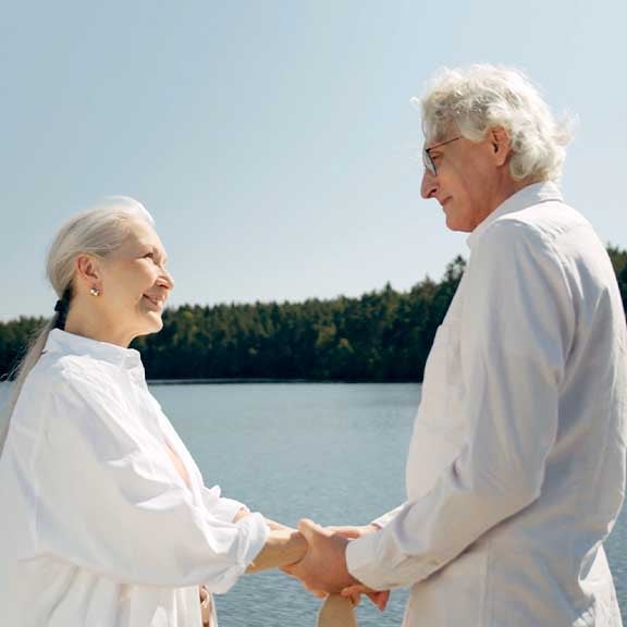 Frau und Mann halten Händen zusammen in der Natur mit See und Wald im Hintergrund