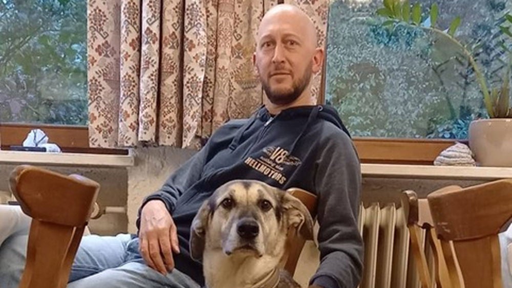 Dirk sitzt mit seinem Hund im Wohnzimmer ©privat