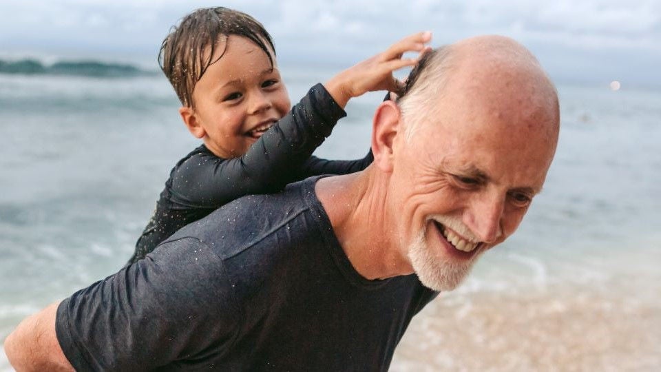 Großvater spielt mit seinem Enkel am Strand.