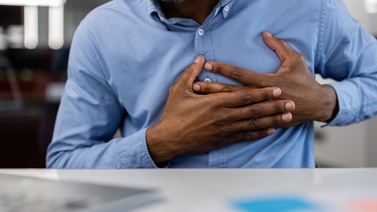 Mann mit Brustschmerzen, der die Brust mit Unbehagen hält und ein blaues Hemd trägt, Bildquelle: ©Adobe Stock/Liubomir