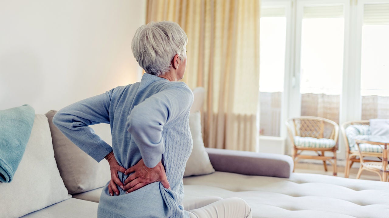 Seniorin in blauem Pullover mit Rückenschmerzen, Bildquelle: ©Adobe Stock/Jelena Stanojkovic 