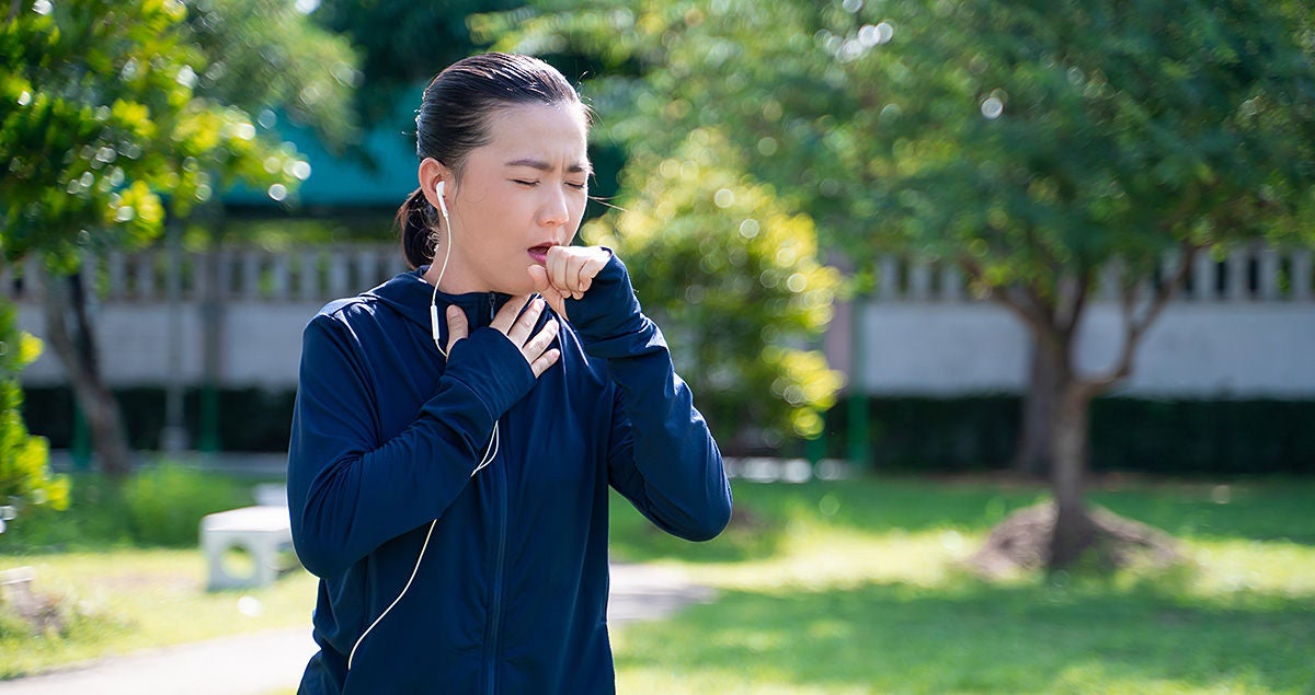 Eine Frau hustet beim joggen