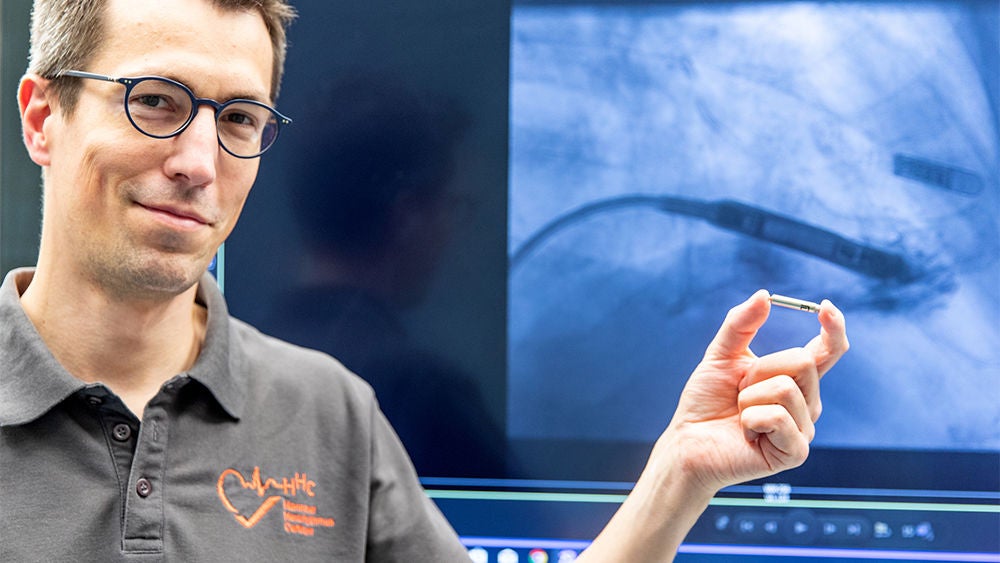 Prof. David Duncker hält den kleinen kapselförmigen Herzschrittmacher zwischen zwei Fingern.