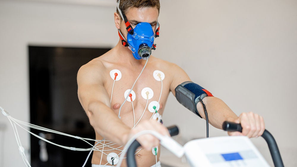 Eine Frau sitzt erschöpft auf dem Sofa und hält sich ihr Herz.