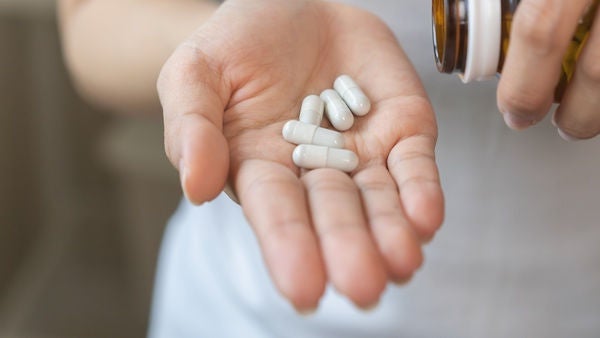 Ein Mann hält Tabletten in seiner Hand.