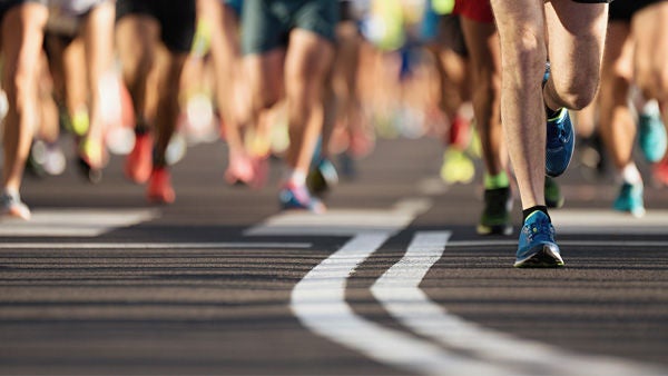 Die bunten Turnschuhe zahlreicher Menschen, die einen Marathon in einer Stadt laufen. Bildquelle: iStock/Pavel1964