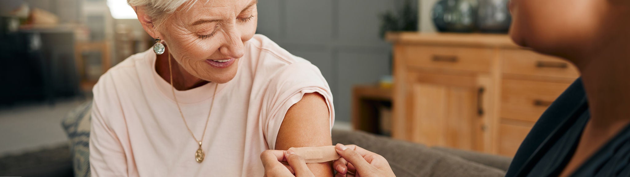 Eine Frau bekommt nach der Grippe-Impfung ein Pflaster auf den Oberarm geklebt.