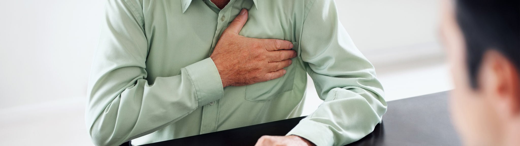 Ein Mann hält die Hand an die schmerzende Brust.