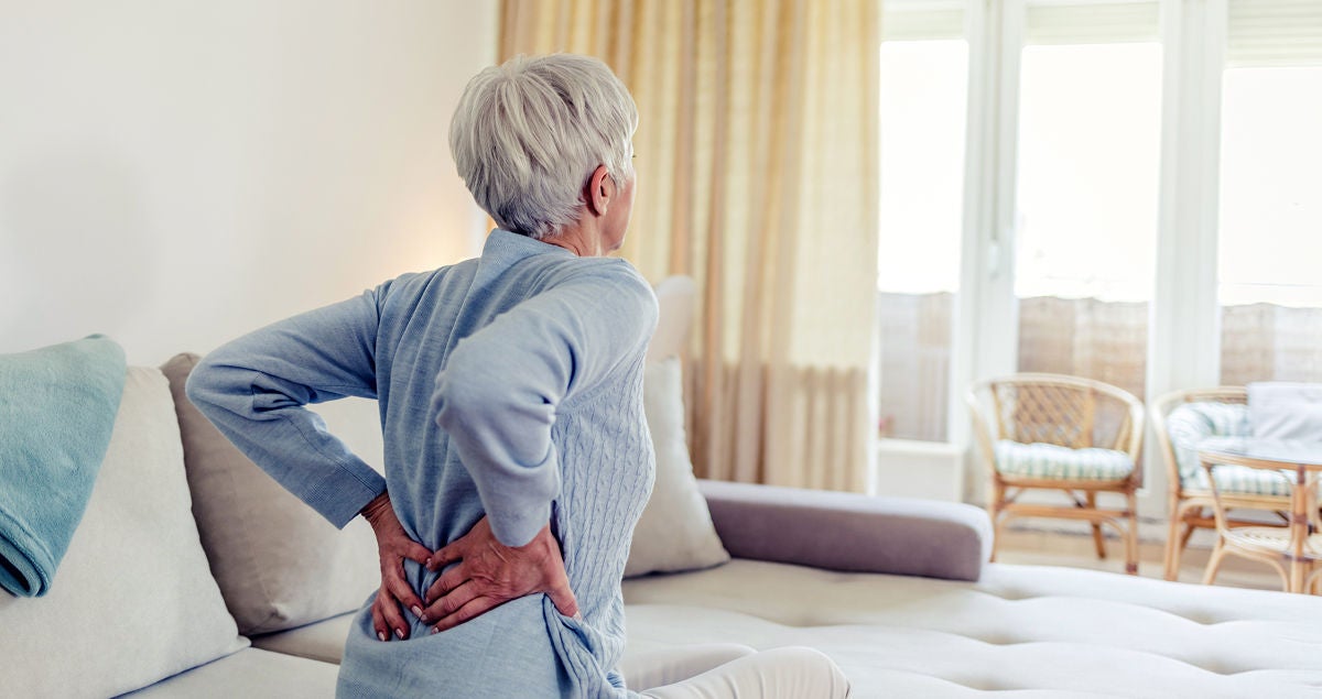 Seniorin in blauem Pullover mit Rückenschmerzen, Bildquelle: ©Adobe Stock/Jelena Stanojkovic 