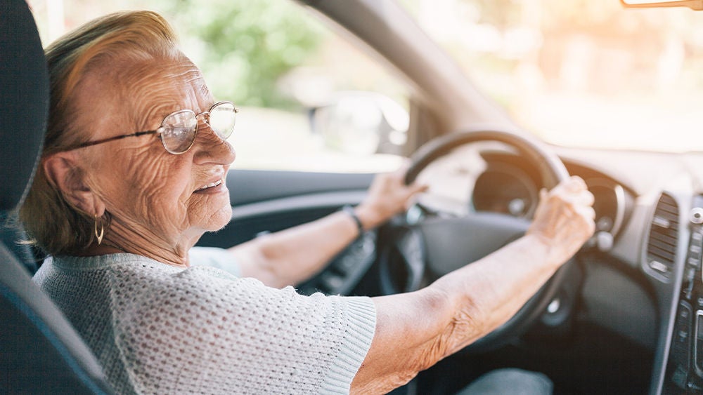 Eine ältere Frau lenkt ein Auto.