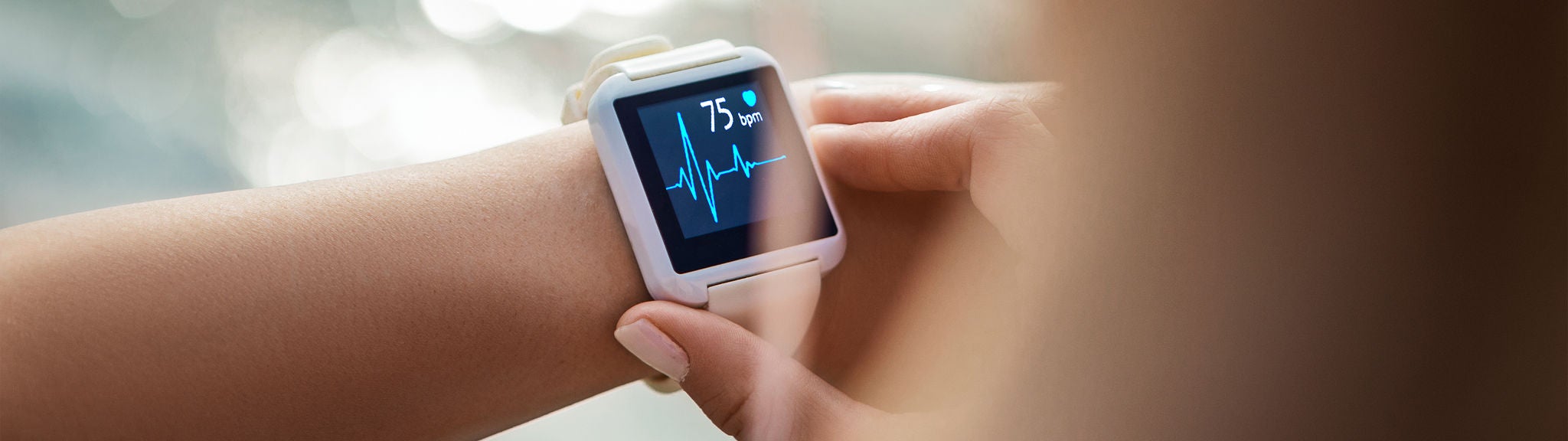 Eine Frau prüft ihre Herzfrequenz auf einer Smartwatch.