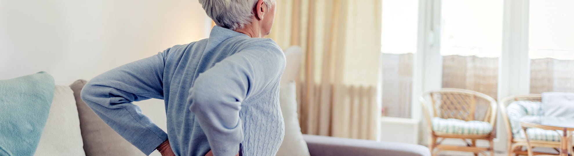 Seniorin in blauem Pullover mit Rückenschmerzen, Bildquelle: ©Adobe Stock/Jelena Stanojkovic 