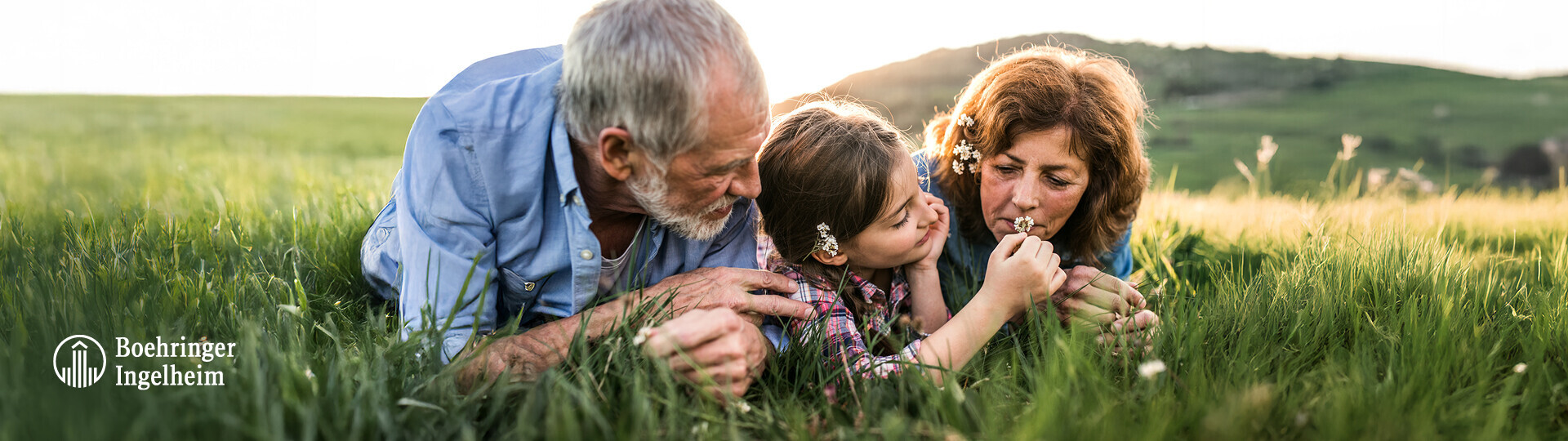 Kind liegt mit Großeltern auf einer Wiese