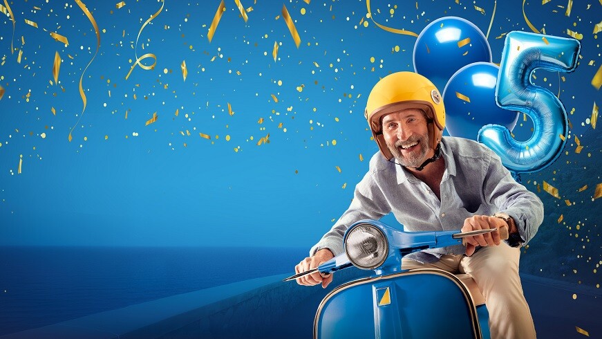 Gut gelaunter Mann sitzt auf einem Mofa mit Ballons