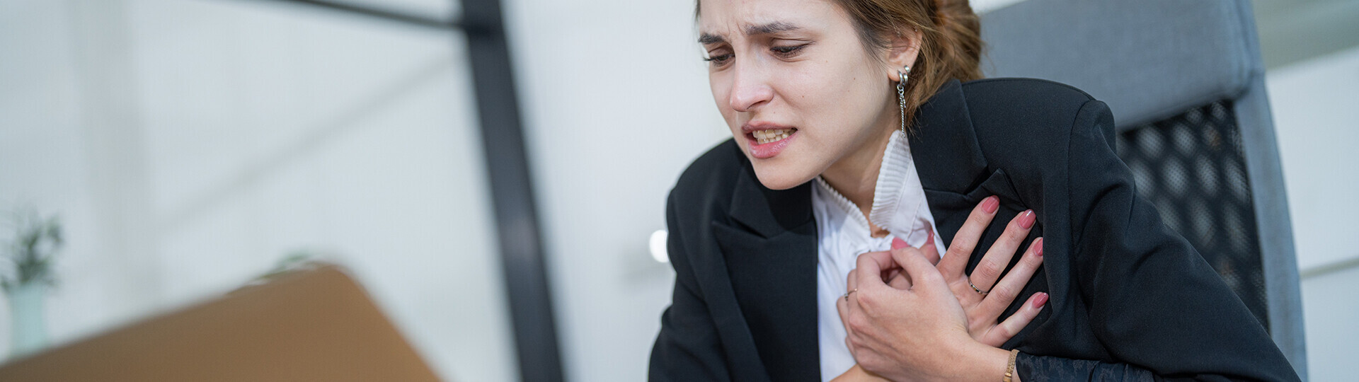 Frau fasst sich an den Brustkorb
