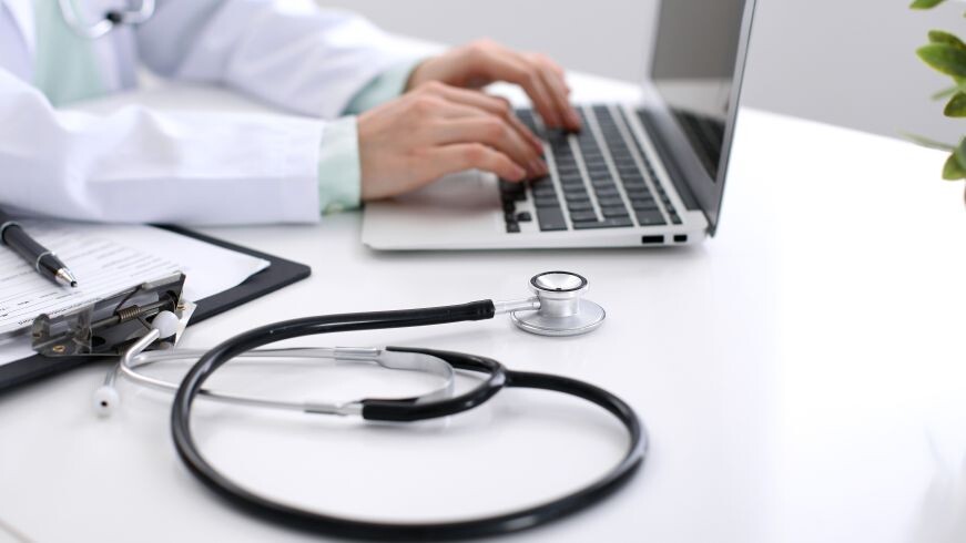 Hände am Laptop plus Stetoskop