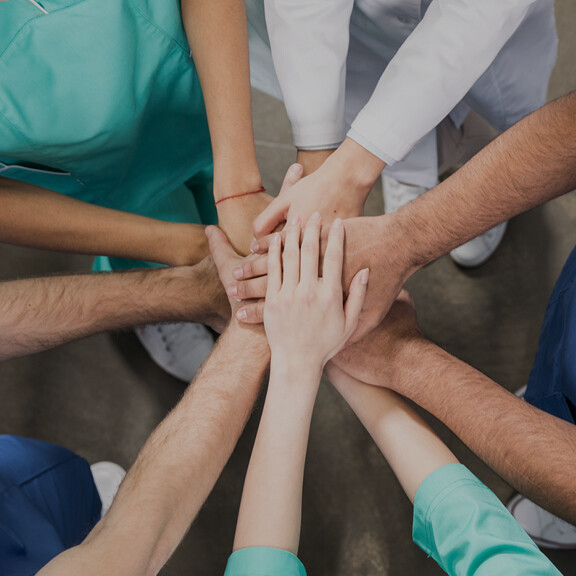 kollegen-halten-haende-zusammen-shutterstock-629115215-1zu1-576x576px-dunkel