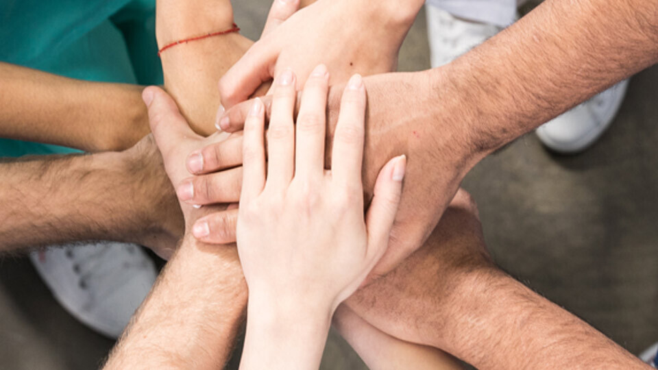 kollegen-halten-haende-zusammen-shutterstock-629115215-32zu9-1920x540px