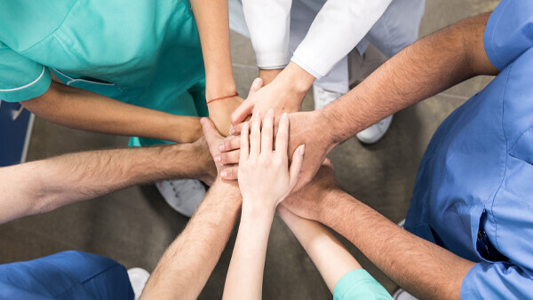 kollegen-halten-haende-zusammen-shutterstock-629115215-600x338px