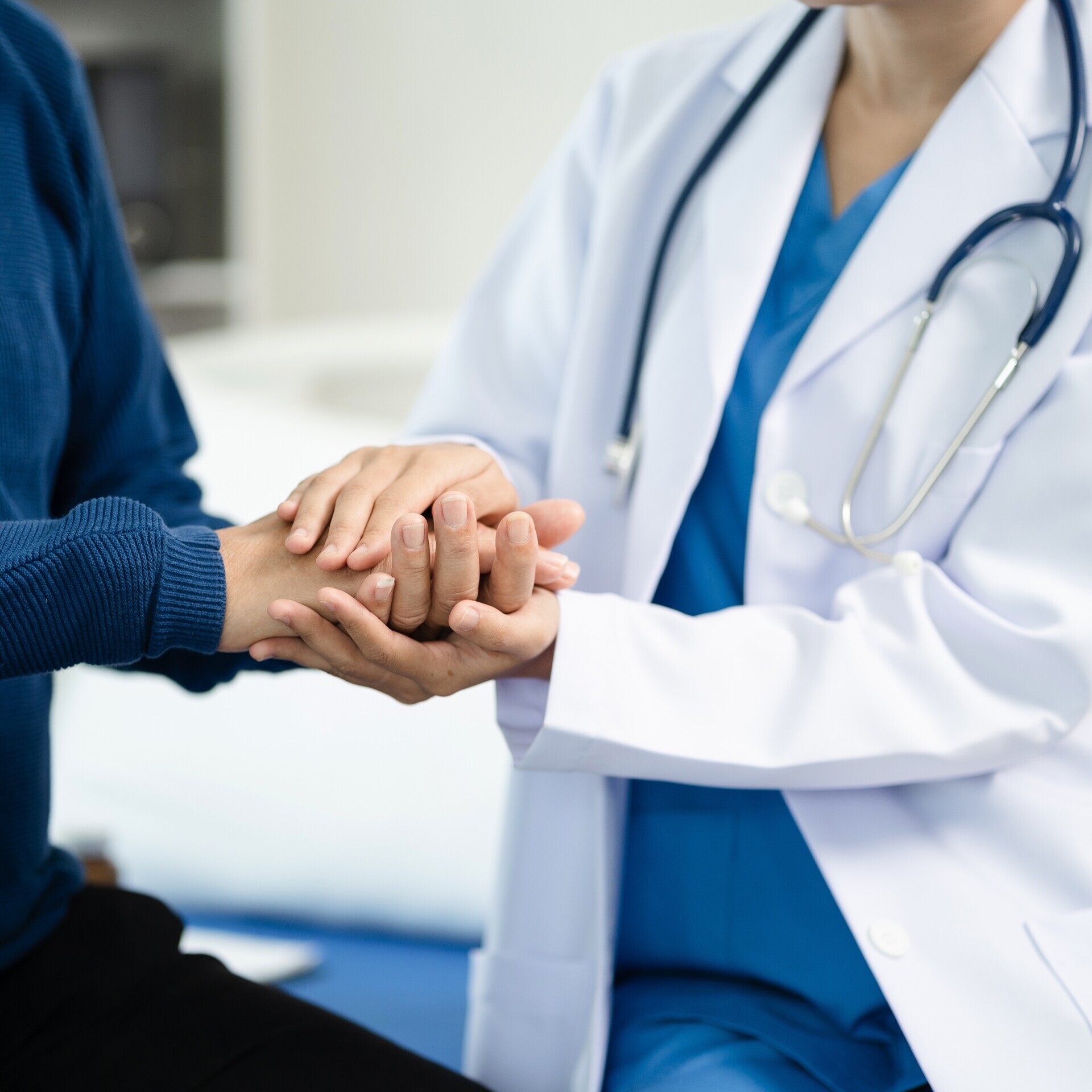 Ärztin hält Hand von Patient