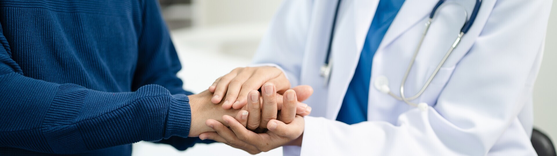 Ärztin hält Hand von Patient