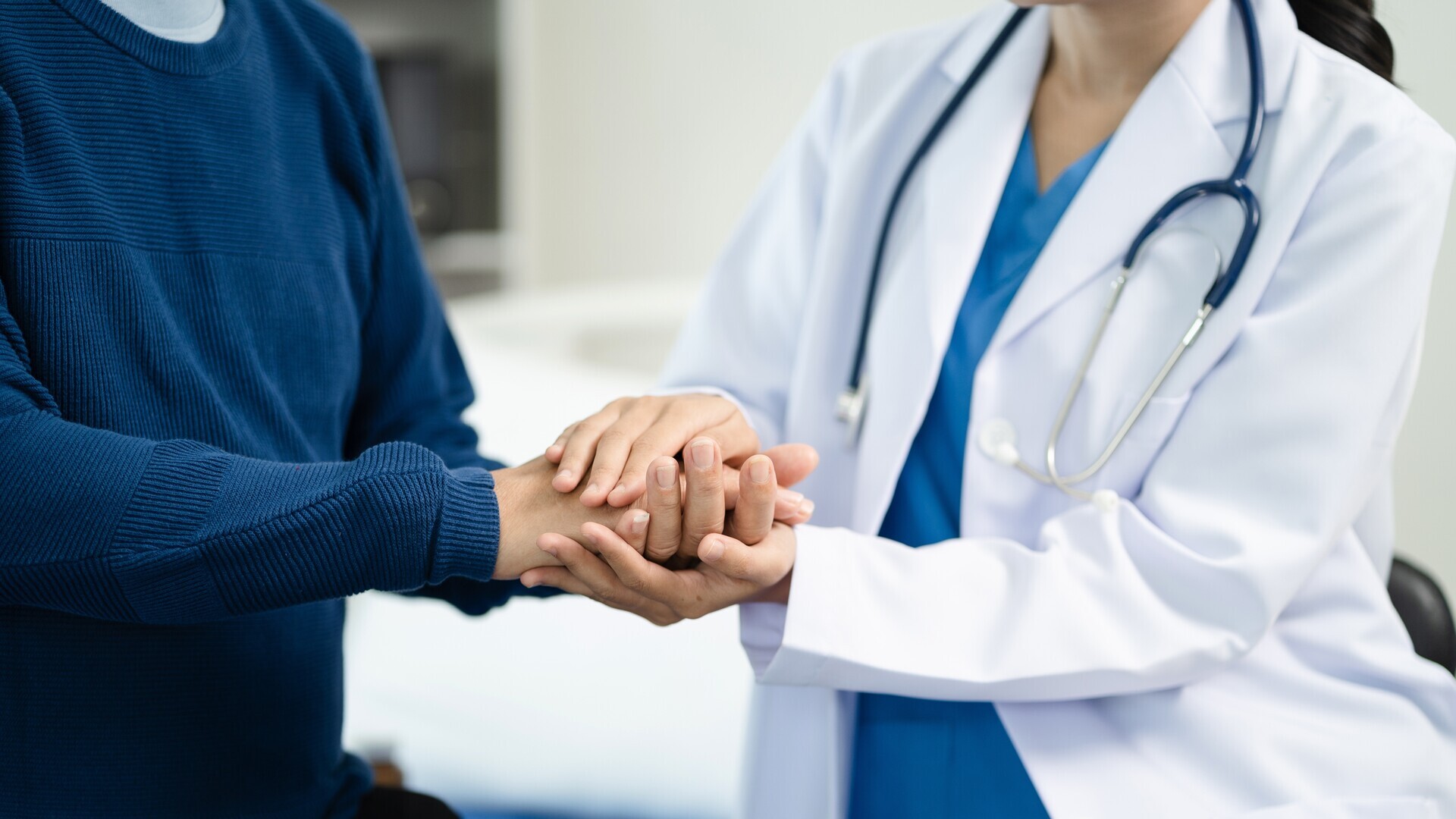 Ärztin hält Hand von Patient