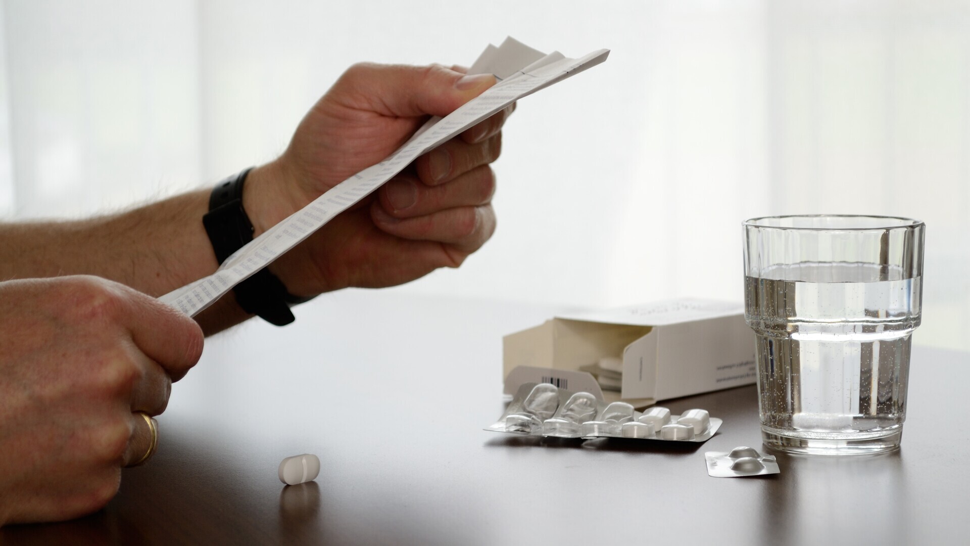 Person liest Beipackzettel von Medikament