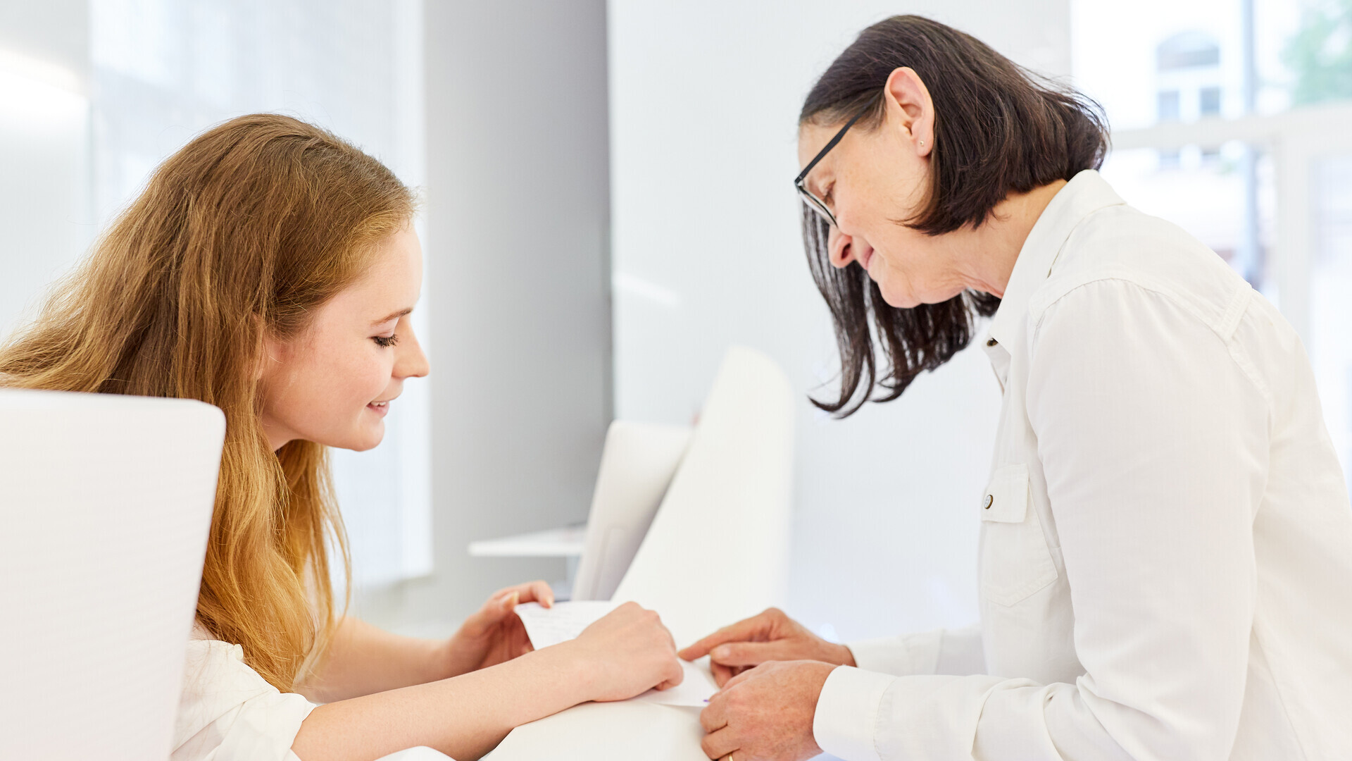 Patient and doctor's assistant at the reception counter of a doctor's practice when registering