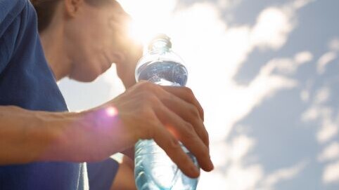 frau bei hitze trinkt wasser