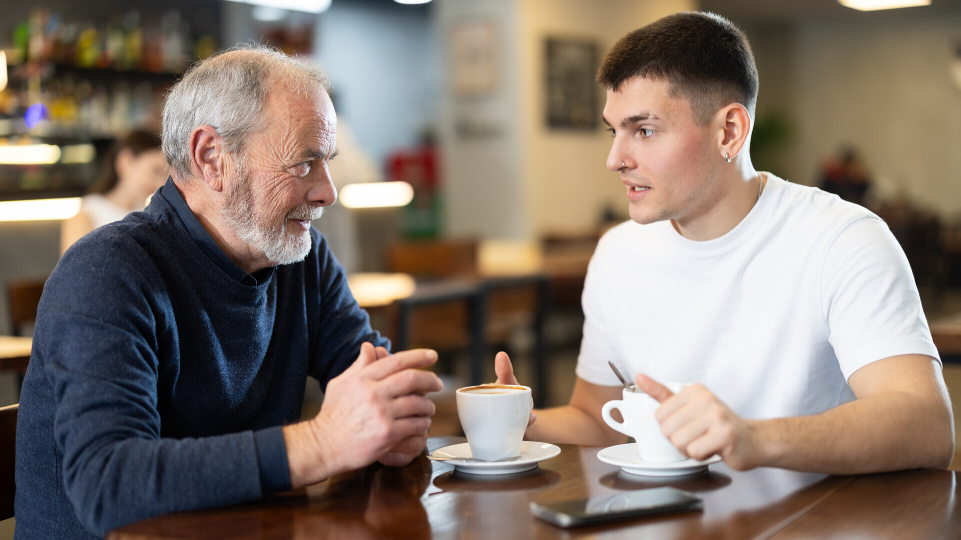 Junger Mann sitzt mit älteren Mann in einem Cafe