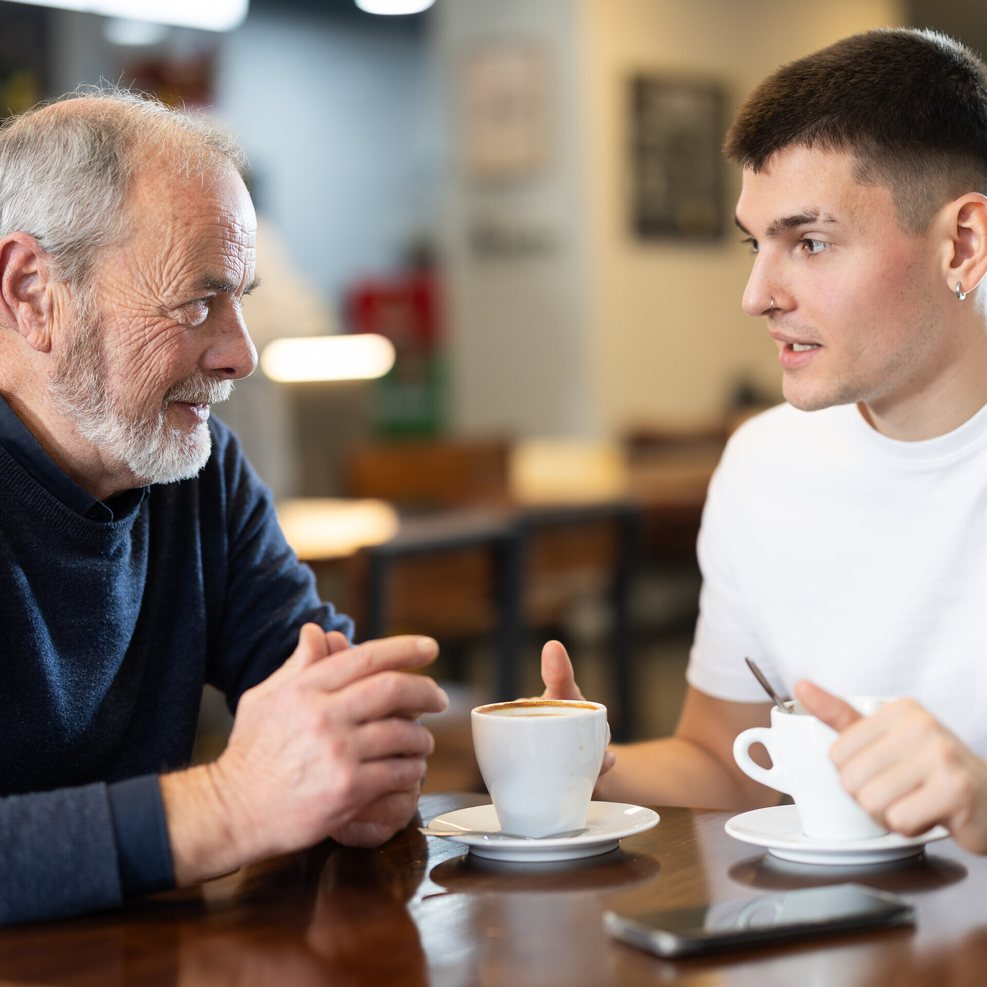 Junger Mann sitzt mit älteren Mann in einem Cafe