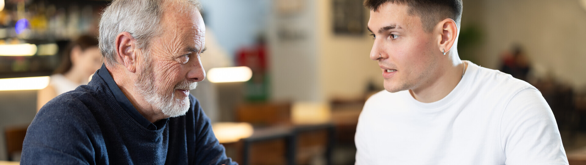 Junger Mann sitzt mit älteren Mann in einem Cafe