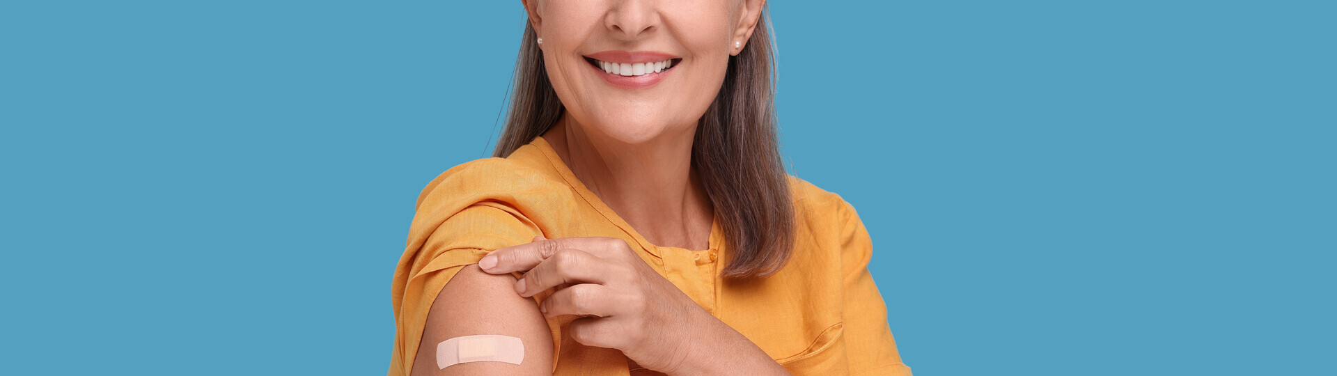 Ältere Frau mit einem Pflaster auf dem Arm nach einer Impfung
