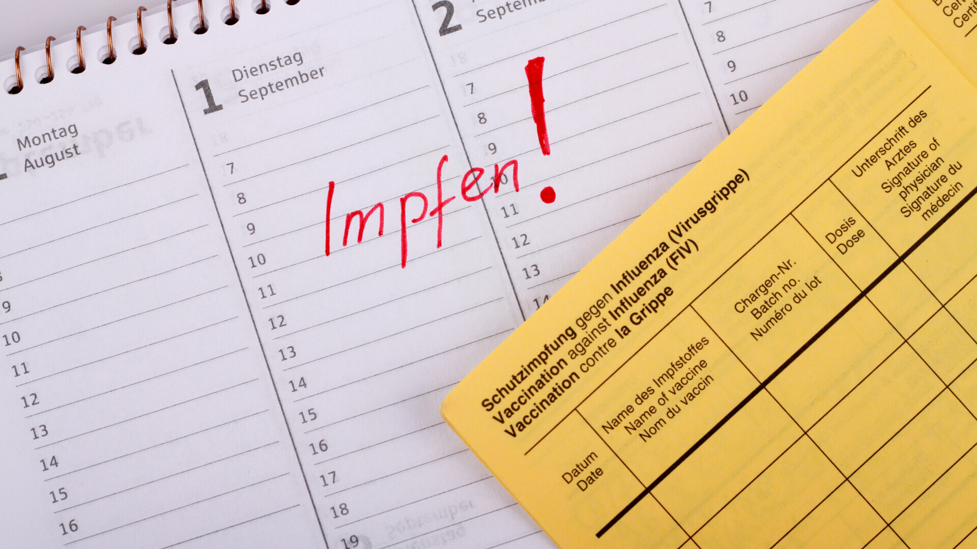 Impfpass liegt auf Kalender mit markierten Termin