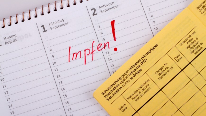 Impfpass liegt auf Kalender mit markierten Termin