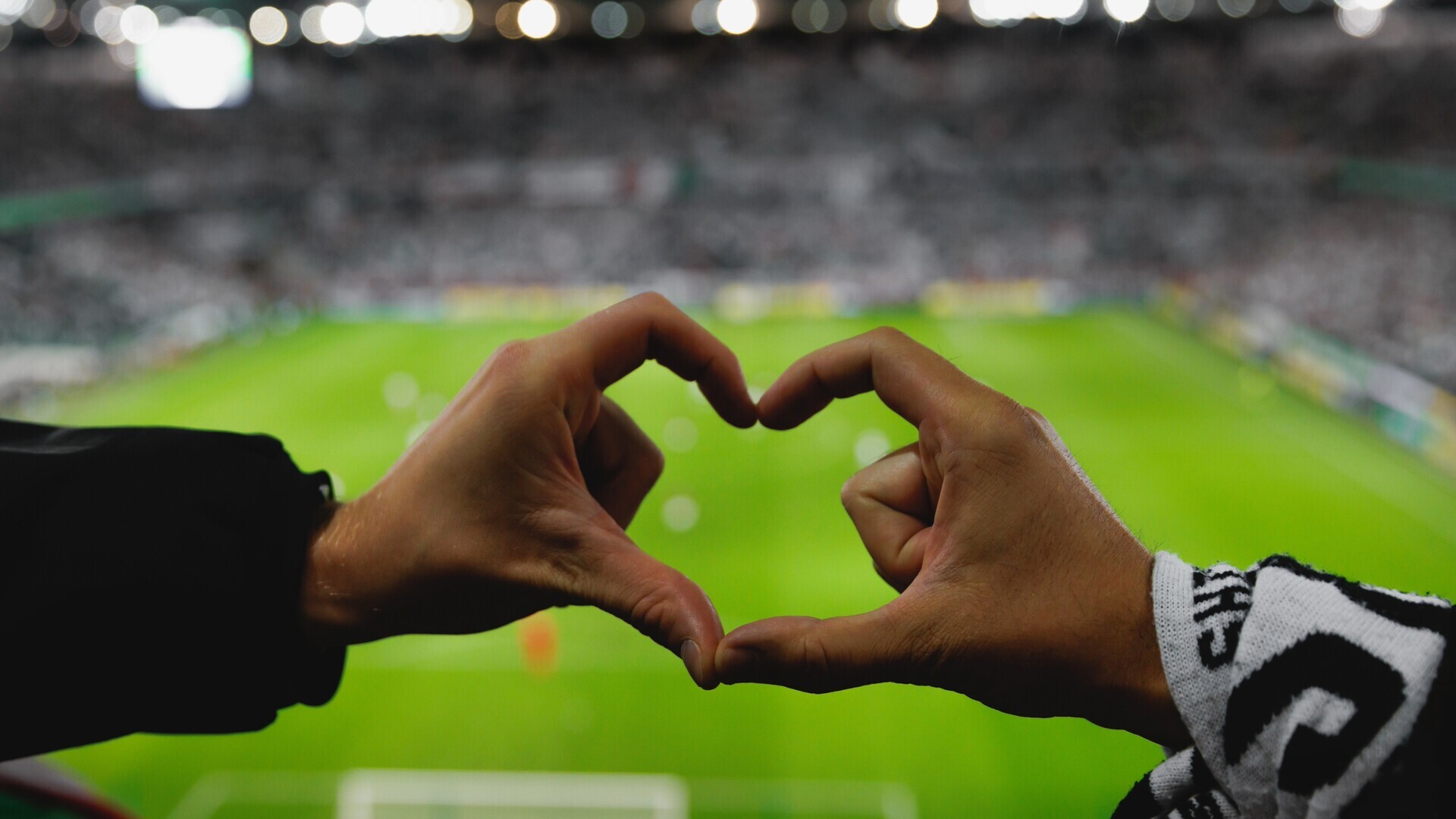 Hände formen Herz auf Stadiontribüne