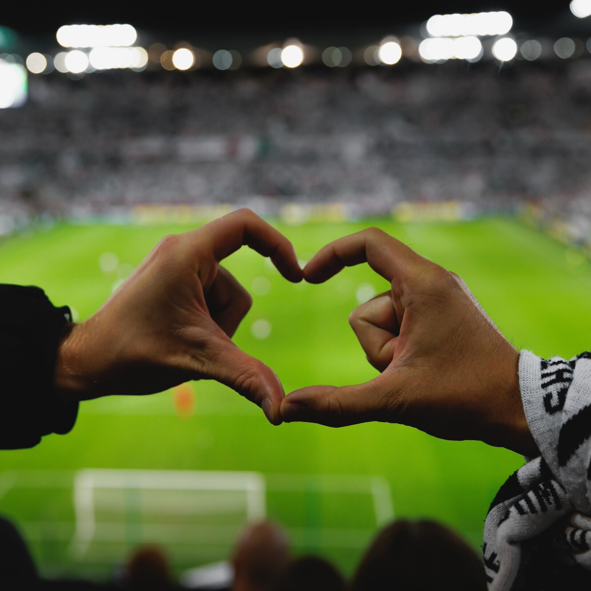 Hände formen Herz auf Stadiontribüne