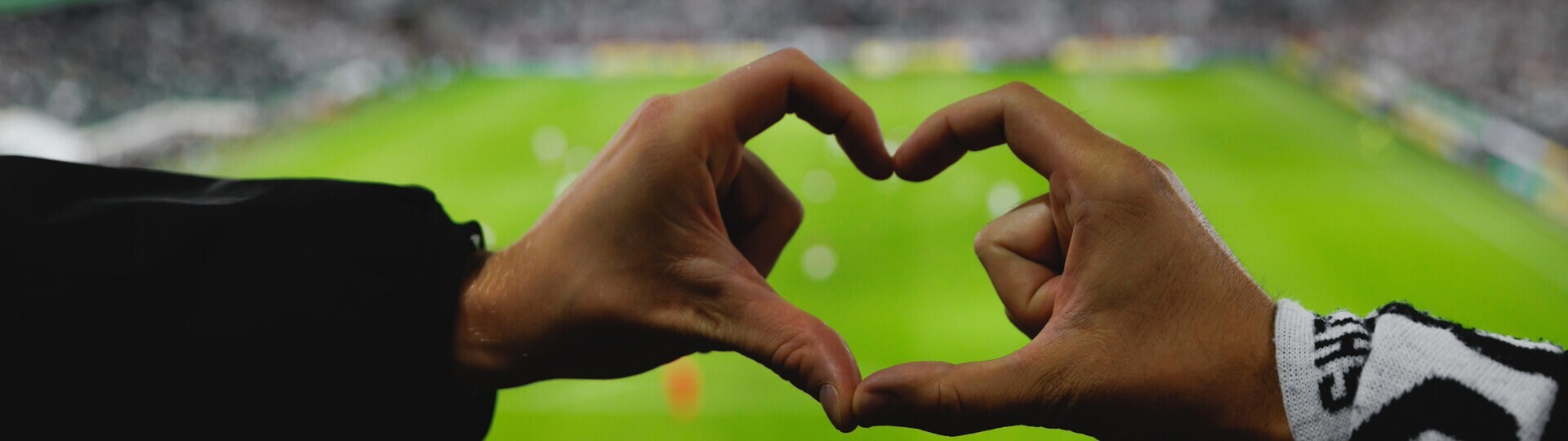 Hände formen Herz auf Stadiontribüne